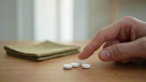 Рука дотрагивается до белой таблетки